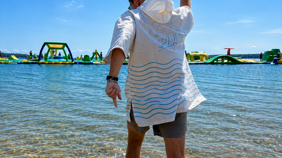 Person walking in shallow water towards floating inflatables on a sunny day.