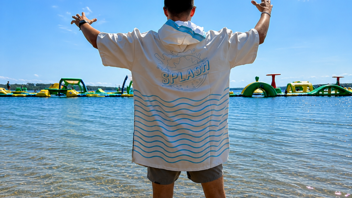 Person standing in shallow water facing inflatable obstacles on a lake.