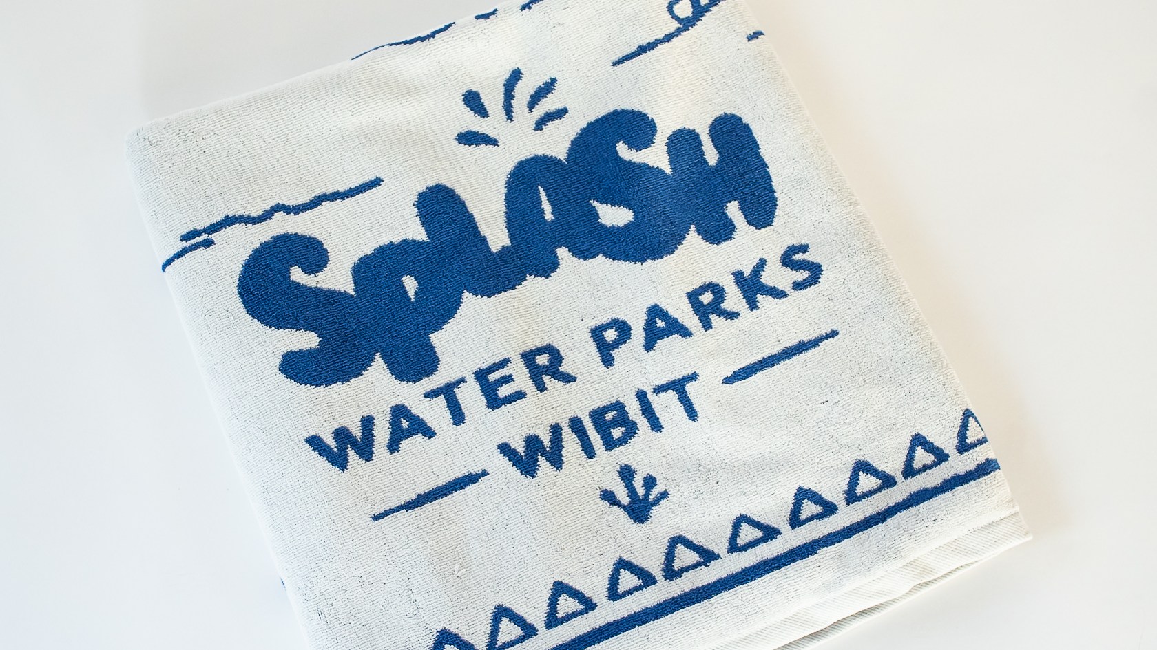 Folded white towel with 'Splash Water Parks Wibit' in blue print.