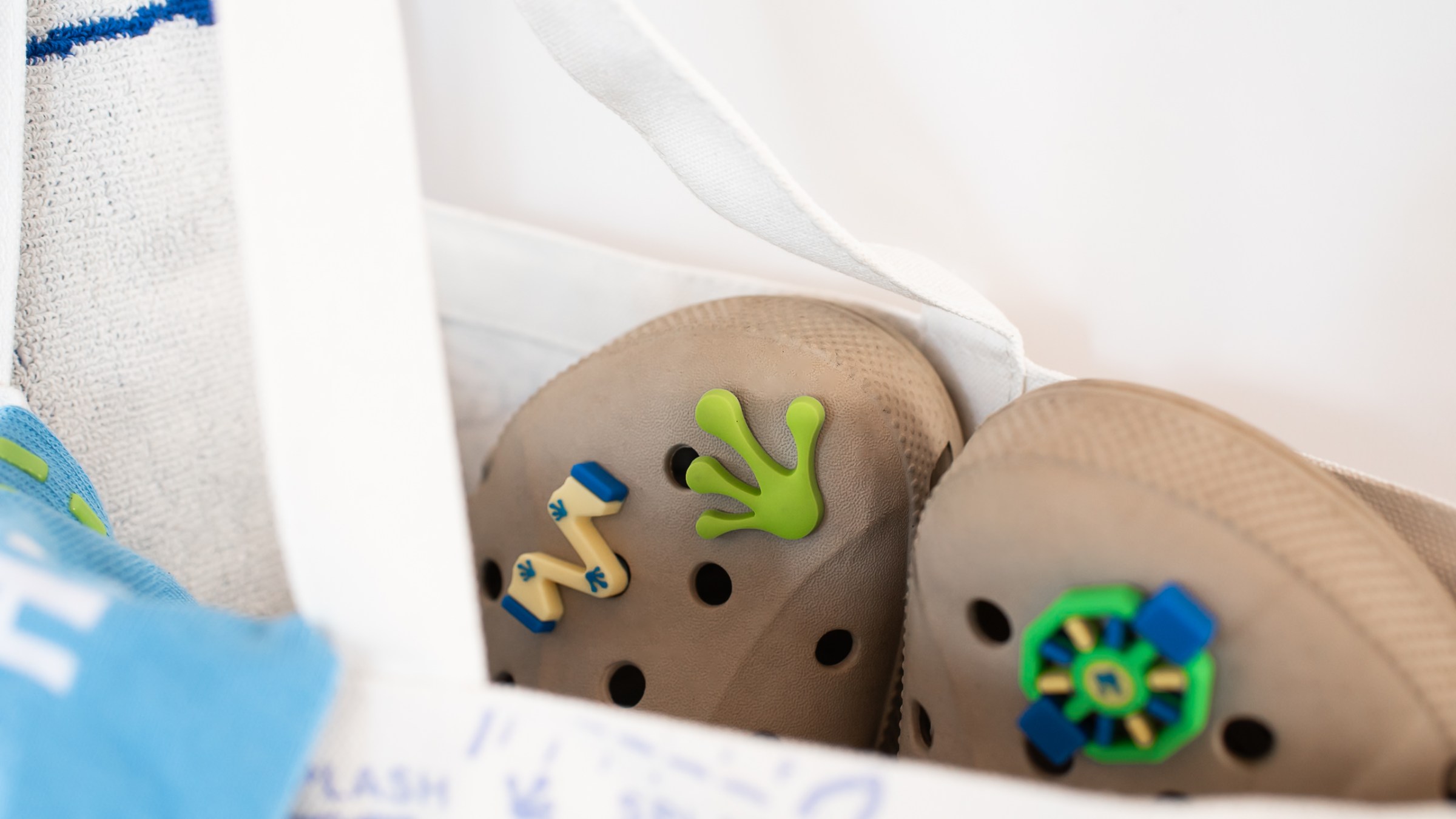 Beige clogs with colorful charms in a white bag.