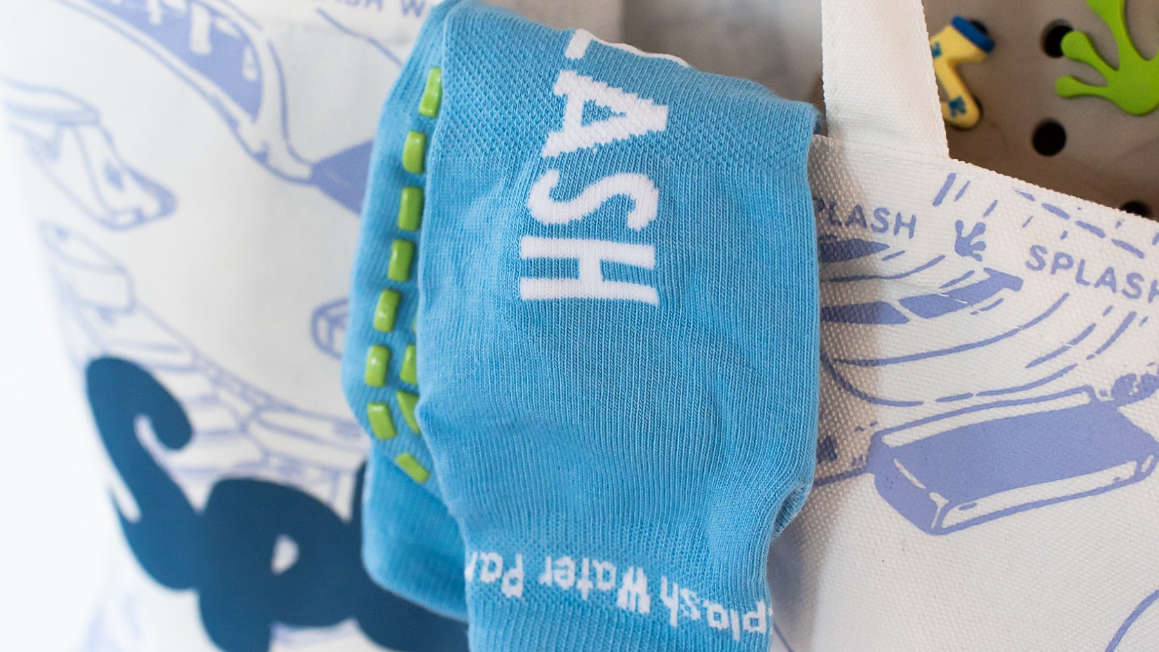 Tote bag with 'Splash' print and a blue sock hanging out.